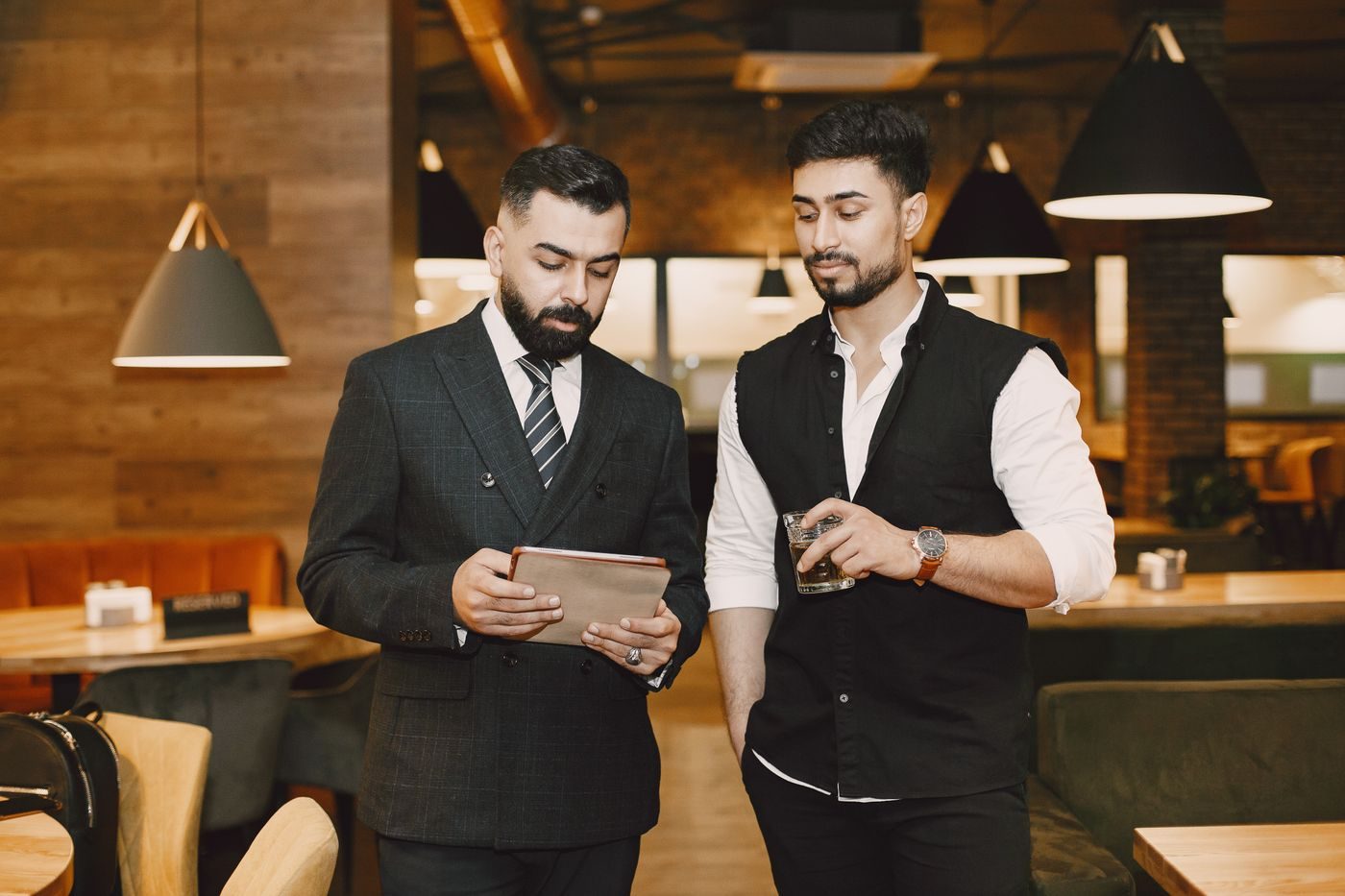 Venue manager reviewing the evening on a tablet with a colleague in a restaurant